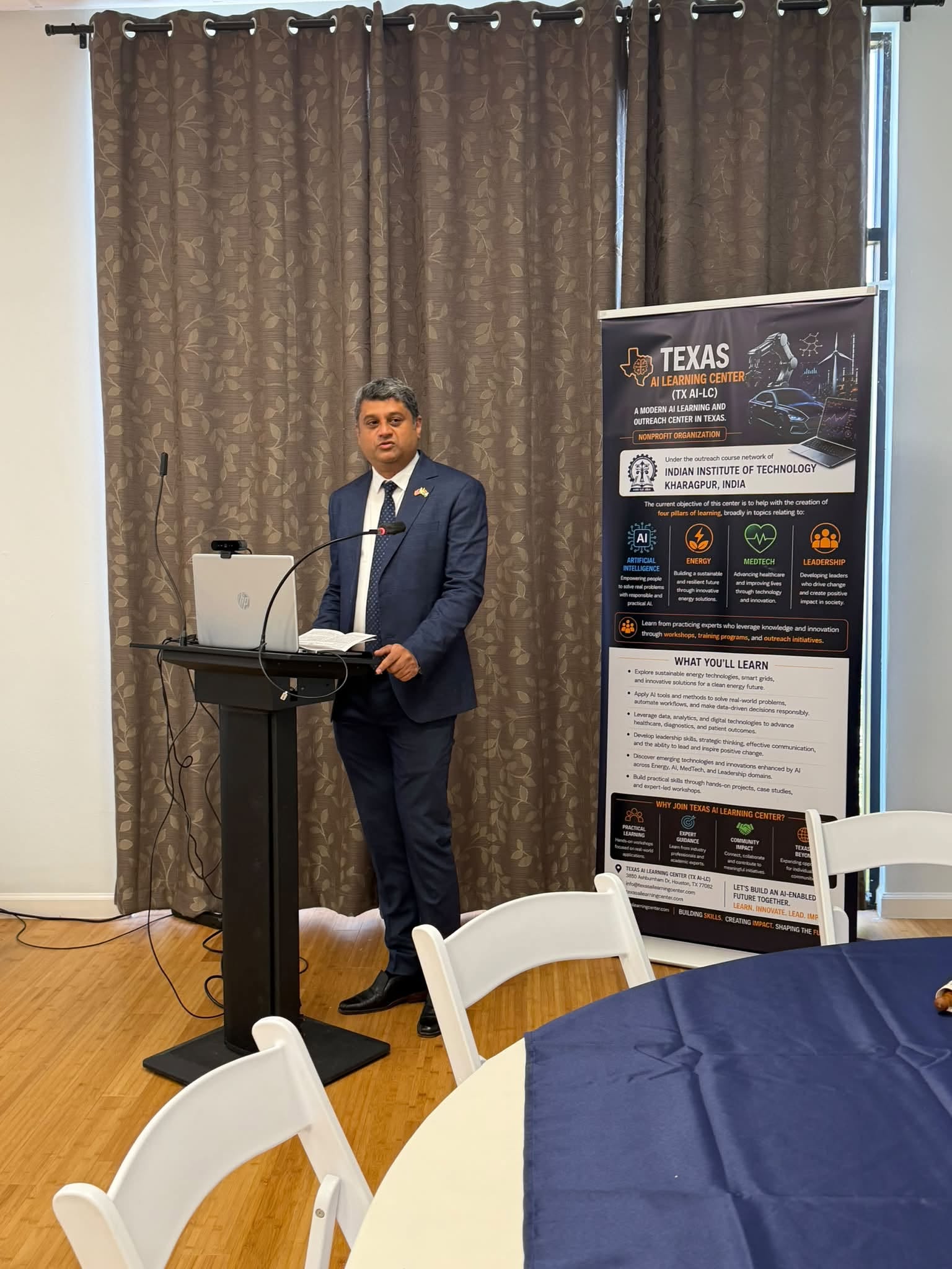 A TX AI-LC speaker presenting at a Texas AI Learning Center outreach event, with the Center's banner displayed behind the podium.